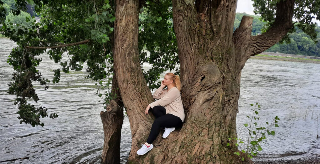 Hobby-Fotografin Nadine Weiß sitzend auf einem Baum am Wasser
